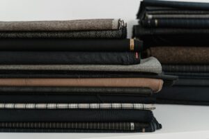 A neatly arranged pile of diverse fabrics, ideal for a fashion designer or tailor's workshop.